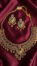 Gold necklace with pink and green gemstones.