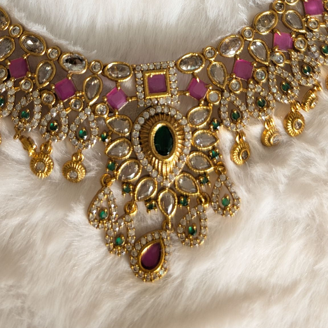 Gold necklace with pink and green gemstones.