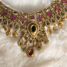 Gold necklace with pink and green gemstones.