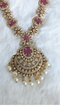Gold necklace with white and pink stones and matching earrings.