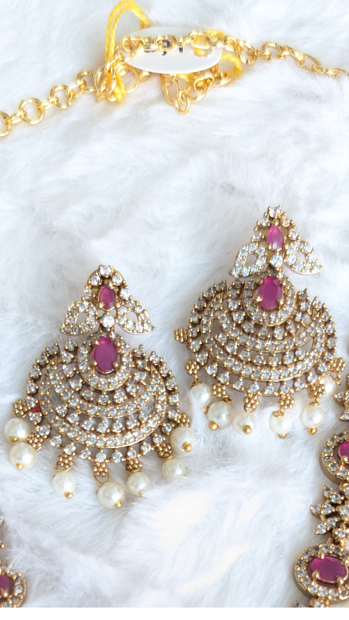 Gold necklace with white and pink stones and matching earrings.