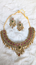 Gold necklace with pink and green gemstones.