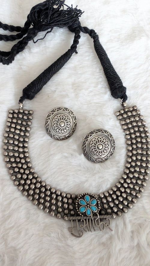 Silver necklace and earrings with a black cord on a white background