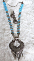 Necklace with blue beads and ornate silver pendant.
