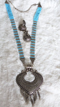 Necklace with blue beads and ornate silver pendant.