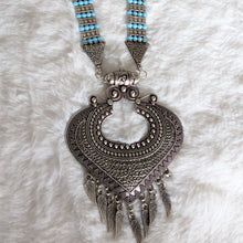 Necklace with blue beads and ornate silver pendant.
