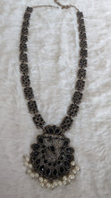 Decorative necklace with intricate design and pearl accents.