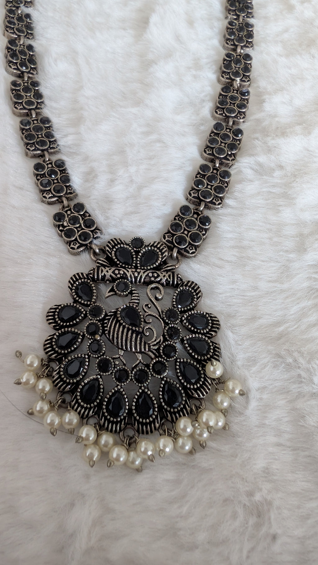 Ornate necklace with a large pendant and pearl accents.