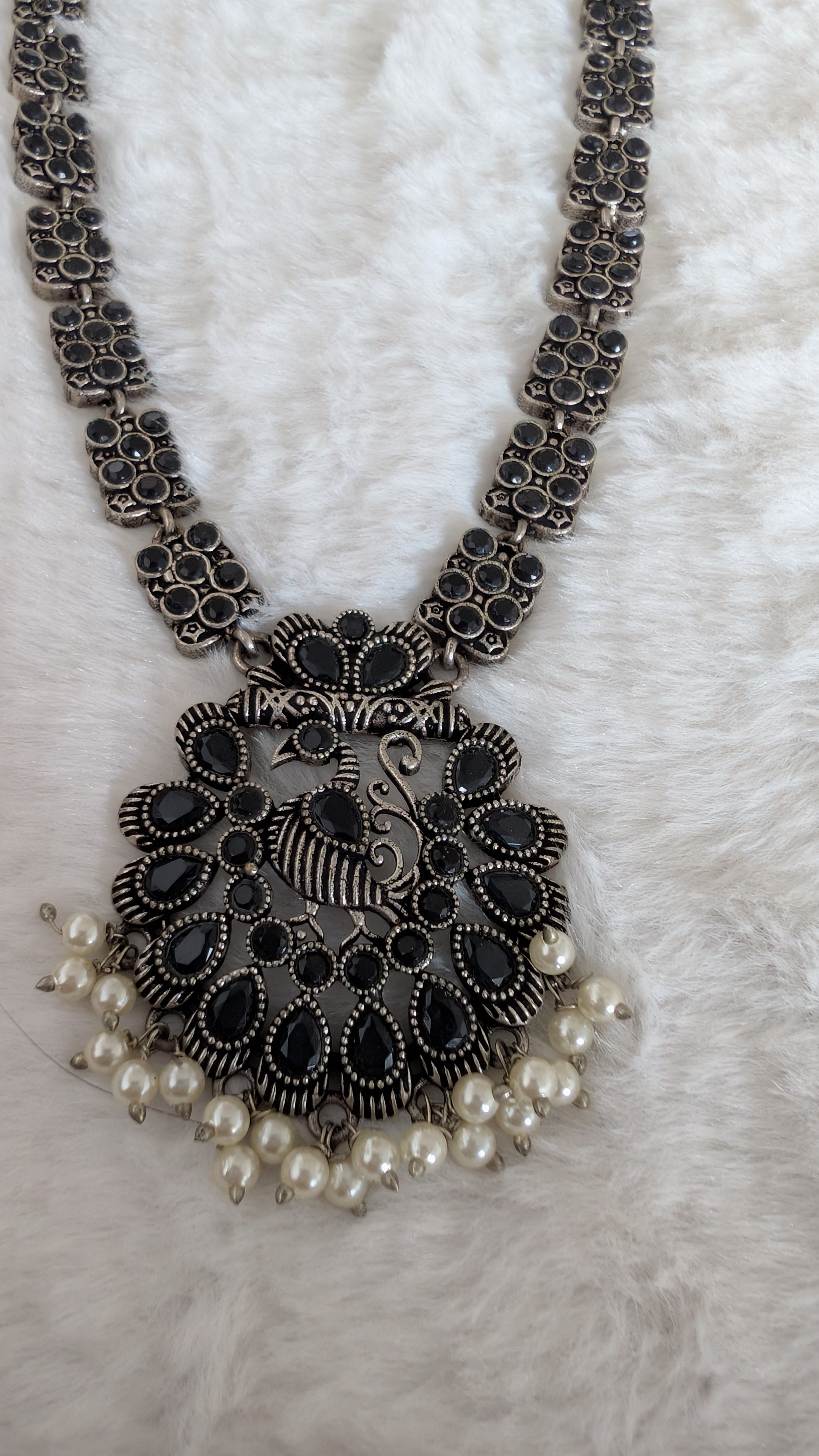 Ornate necklace with a large pendant and pearl accents.