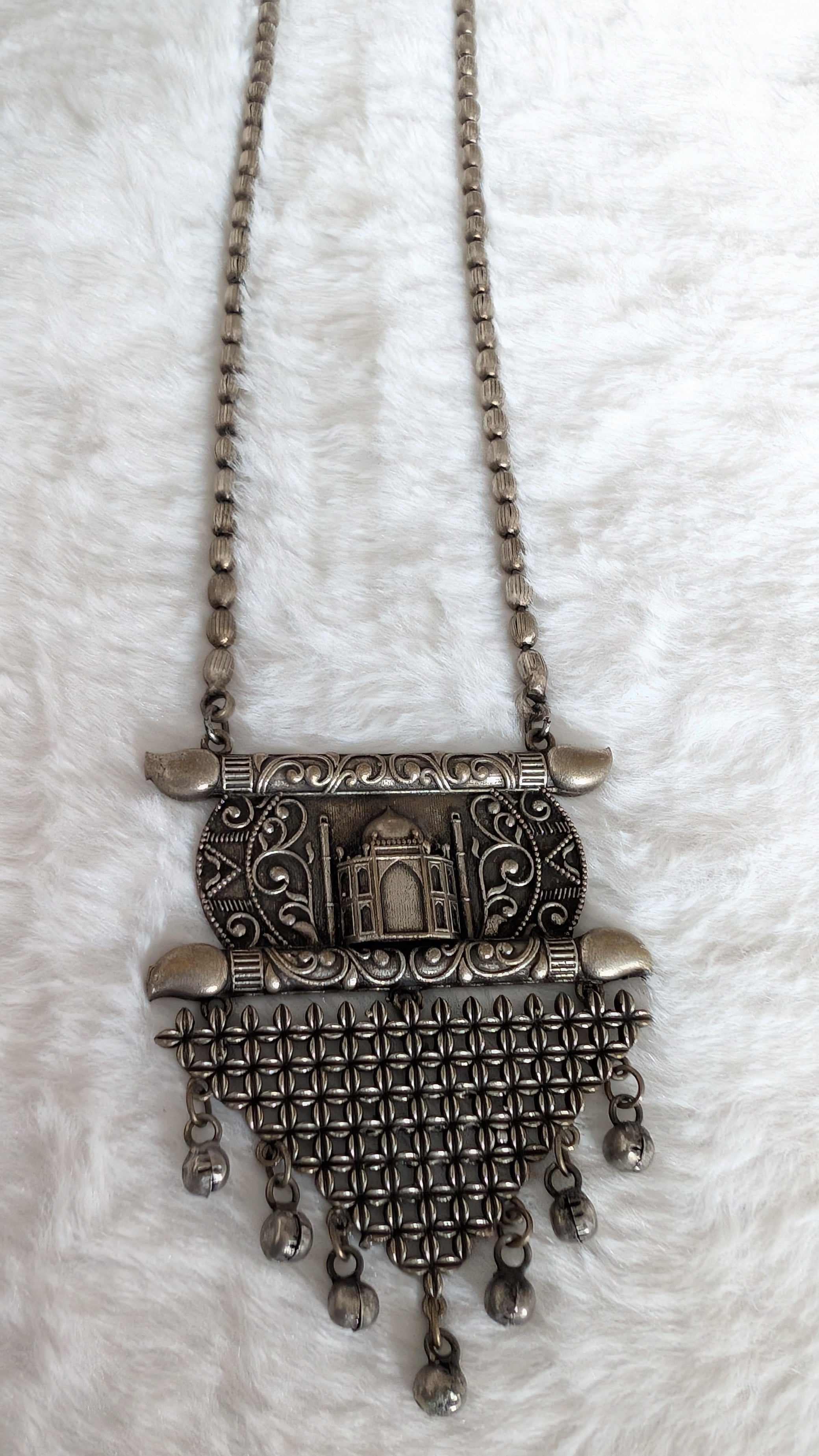 Oxidized silver necklace with intricate design on a white background
