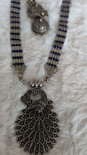 Necklace with intricate silver pendant and blue beads.