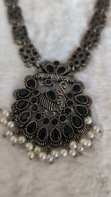 Decorative necklace with intricate design and pearl accents.